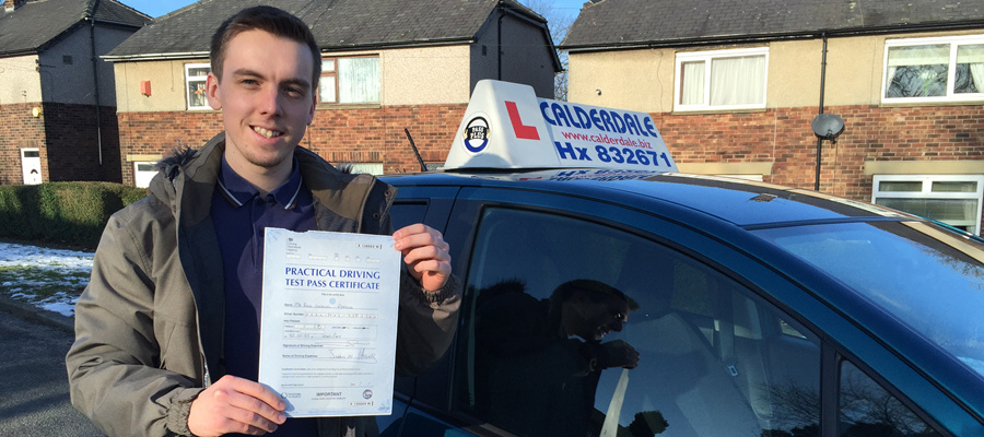 A pupil holding his driving test pass certificate next to the Calderdale School of Motoring car