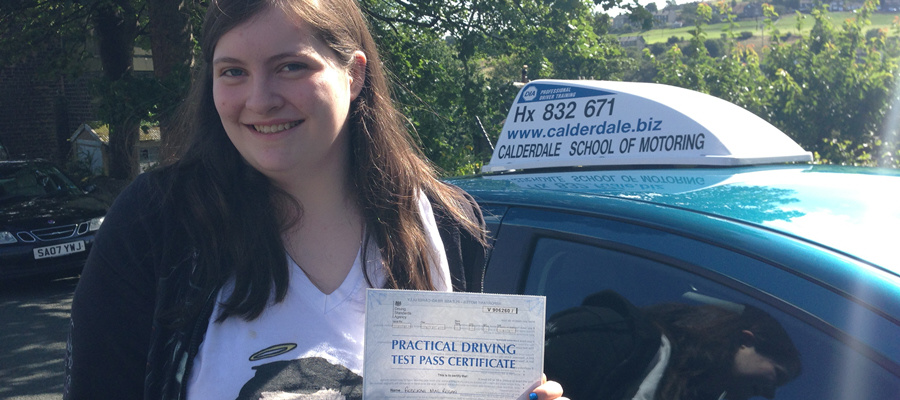 A pupil smiling with her practical driving test pass certificate on a sunny day in Halifax