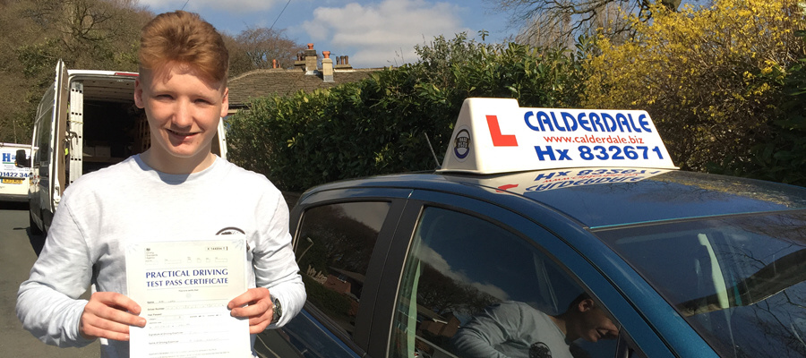A young driver holding his pass certificate beside the Calderdale School of Motoring roof box